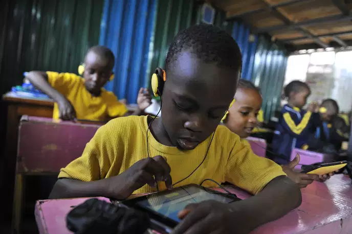 Des élèves de Kawangware, un bidonville de Nairobi, au Kenya, utilisent une tablette créée par une entreprise locale, en octobre 2015. SIMON MAINA / AFP